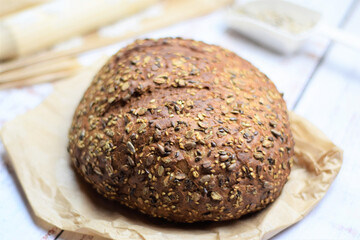 Multigrain bread adding nutritional contribution. On kraft paper bag and rustic white table.