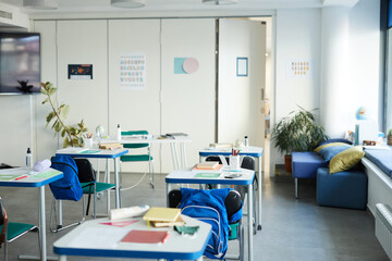 Wide angle background image of desks in row with textbooks and supplies in school classroom interior, copy space
