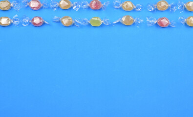Assorted flavored candies on a blue background. Copy space.