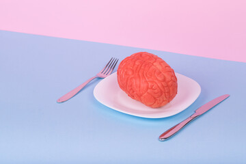 Popular Minimal idea made of the human brain on a plate, fork and knife on a pastel background