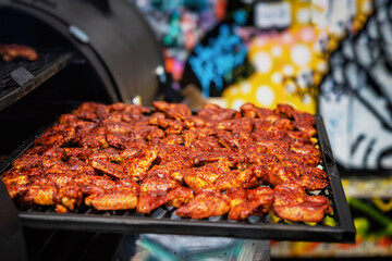 Appetizing crispy chicken wings in spicy marinade, grill close-up outdoors. Concept of summer picnic, backyard barbecue