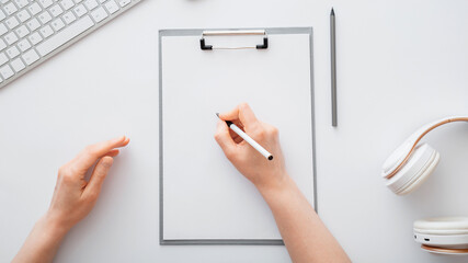Woman writing on empty list in notepad to do list. Female hands do sketching on paper tablet in office workplace. Female hand write in notebook at work desk on white table. Top view Long web banner