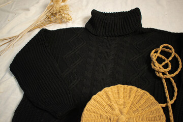 black sweater on white canvas with decorative objects