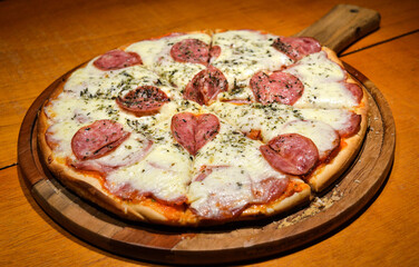 Fresh homemade pepperoni pizza on a wooden plate and rustic table.