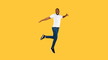 Fototapeta na wymiar Shocked African American Guy Jumping Looking At Camera, Yellow Background