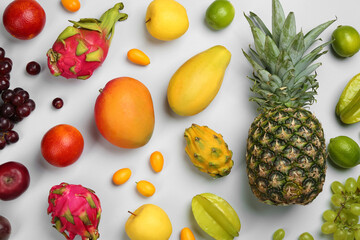 Many different delicious exotic fruits on light background, flat lay