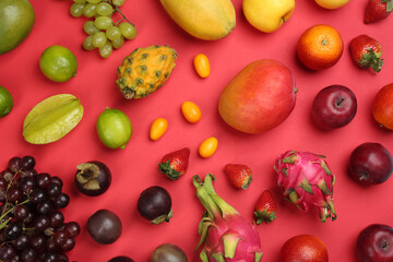 Many different delicious exotic fruits on red background, flat lay