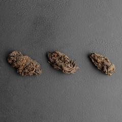 Three pu-erh leaves in bud on dark gray background Lao Cha Tou top view