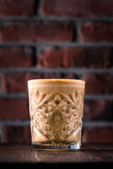 Flat white coffee in transparent glass on wooden table. It is espresso coffee with microfoam steamed milk