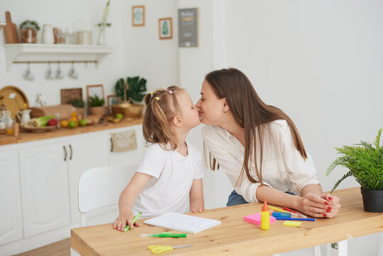 Mom and daughter have finished doing their homework, are happy and kiss. The concept of taking care of a child and helping with homework