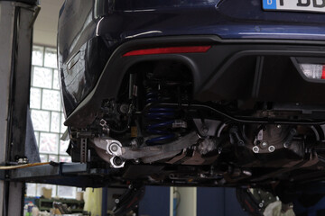 Blue sports car on a lift in the workshop with its tires removed