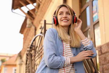 Happy young woman with headphones listening to music on city street