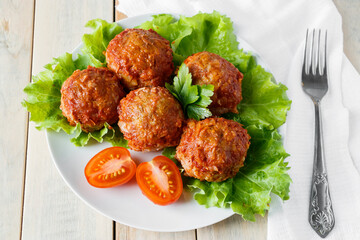 Homemade meat balls with vegetables in tomato sauce. Appetizing protein dish on a plate.