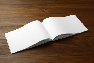 Open blank paper brochure on wooden table. Mockup for design