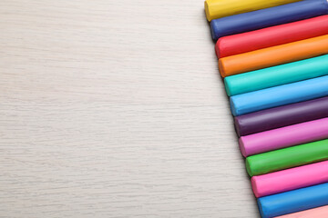 Fototapeta premium Pieces of colorful plasticine on wooden table, flat lay. Space for text