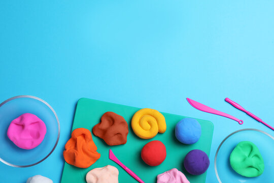 Flat lay composition with colorful plasticine on light blue background. Space for text