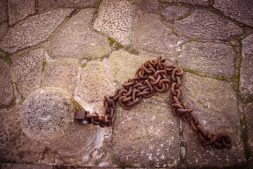 Oxidated chain locked in stone in ancient castle entrance, braga city Portugal