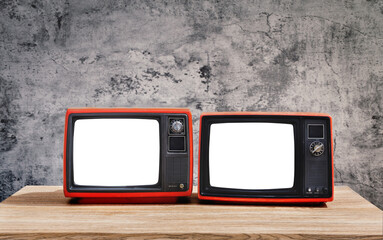 Two old red retro televisions with cut white screen on wooden table in front of the cement wall background.