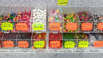 No jelly and vegetarian candies in plastic boxes on a stone shelf, close-up side view.