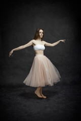 Fototapeta premium Young girl in white top and peach skirt dancing