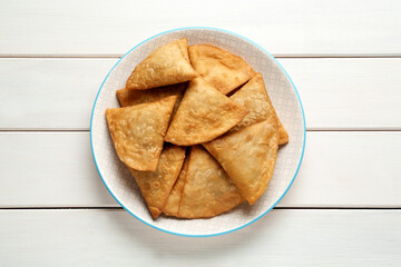 Fresh delicious crispy samosas on white wooden table, top view