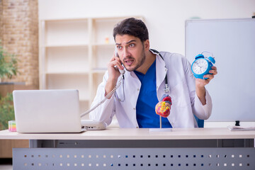 Young male doctor cardiologist in time management concept