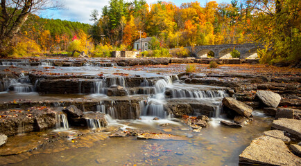 Waterfall in autumn with a scenic background of trees with fall colours and the historic Pakenham...
