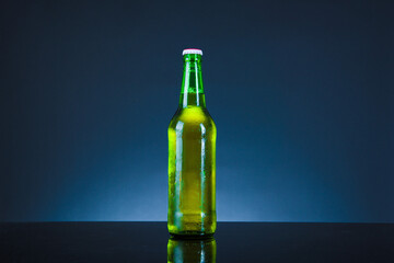 green beer bottle with drops on blue background