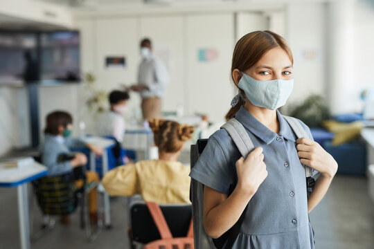 Waist Up Portrait Of Cute Girl Wearing Mask In School Classroom And Looking At Camera , Covid Safety Measures, Copy Space