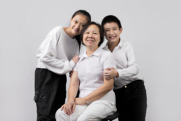 Portrait of Grandmother and grandchild hugging, looking at camera and smiling, on gray background