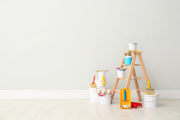 Decorator's kit of tools and paints near light wall indoors. Space for text