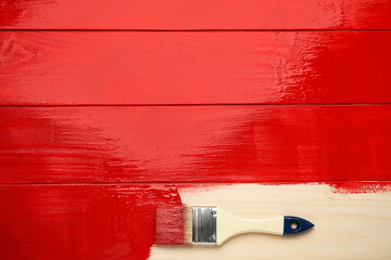 Brush on red painted wooden surface, top view. Space for text