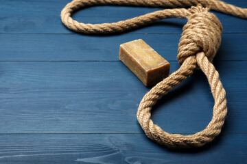 Obraz premium Rope noose and soap bar on blue wooden table. Space for text