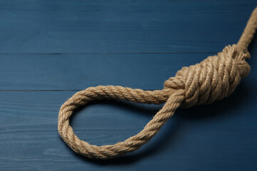 Fototapeta na wymiar Rope noose with knot on blue wooden table, closeup