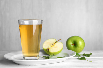 Glass of fresh apple juice on white wooden table