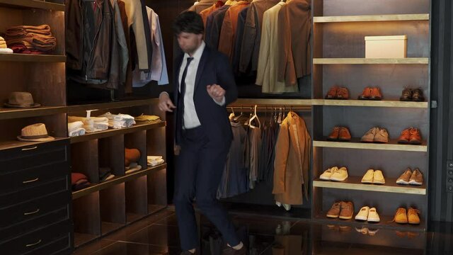 Smiling man dances in a modern suit in the dressing room. A man celebrates success in business