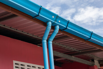 Plastic rain gutter with two downspoutl and background blue sky. plastic guttering system