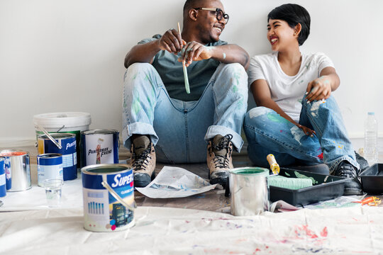 Happy couple painting house wall for interior design
