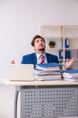 Young male employee unhappy with excessive work in the office