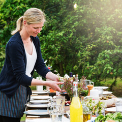 Woman setting a dinner table in a backyard