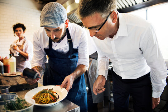 Chef showing garnishing to a man