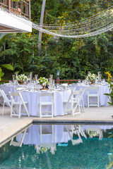 Romantic Wedding Table Top Layout Table Spread no people tropical location with gold cutlery white table cloth and scenic view of sunset with copy space tablescape, beautiful paradise setting