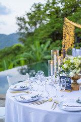 Romantic Wedding Table Top Layout Table Spread no people tropical location with gold cutlery white table cloth and scenic view of sunset with copy space tablescape, beautiful paradise setting
