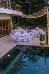 Table Spread no people tropical location with gold cutlery white table cloth and scenic view Romantic Wedding Table Top Layout copy space tablescape soft lighting blue hour