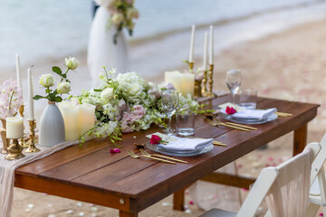 Romantic Wedding Table Top with Red Roses Layout Table Spread no people tropical beach location with gold cutlery and scenic view of sunset on the beach soft light