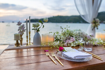 Romantic Wedding Table Top Layout Table Spread no people tropical location with gold cutlery and scenic view of sunset on the beach