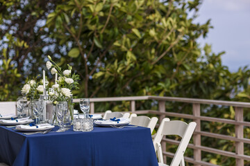 Blue and Silver Romantic Wedding Table Top Layout Table Spread no people catering, event, decor in a tropical location with the sea and clouds in the background