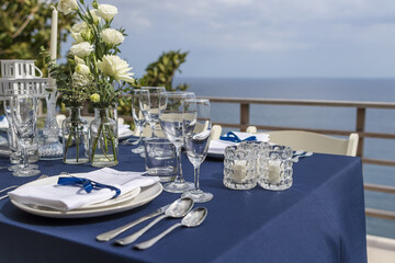 Blue and Silver Romantic Wedding Table Top Layout Table Spread no people catering, event, decor in a tropical location with the sea and clouds in the background