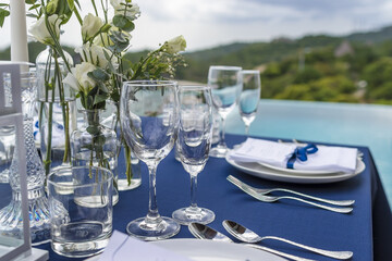 Blue and Silver Romantic Wedding Table Top Layout Table Spread no people catering, event, decor in a tropical location with the sea and clouds in the background