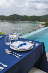 Blue and Silver Romantic Wedding Table Top Layout Table Spread no people catering, event, decor in a tropical location with the sea and clouds in the background